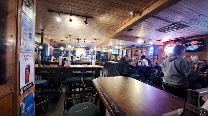 Interior bar at Gatorz with wood ceiling, neon signs and bar stools